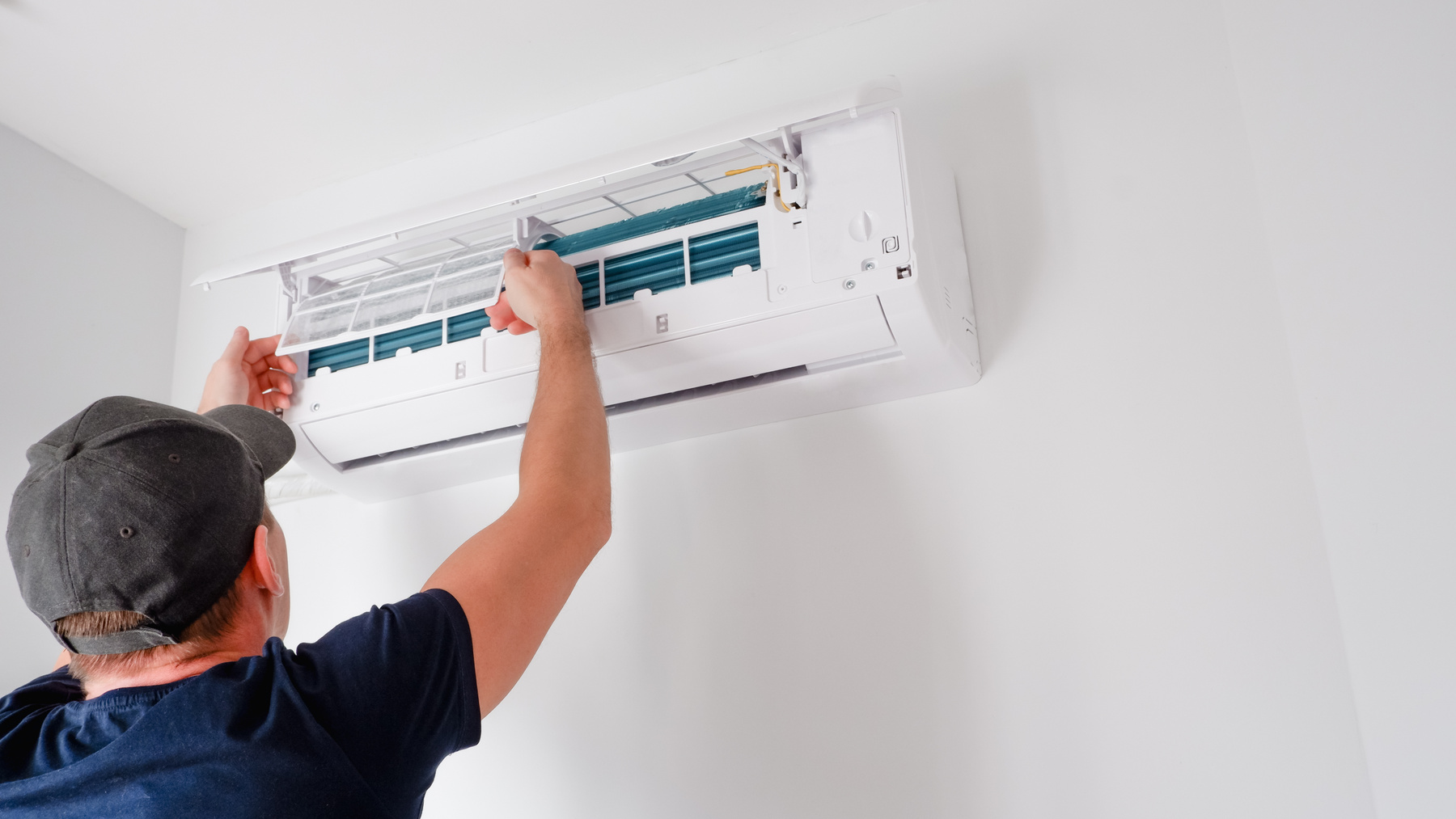 a person fixing an air conditioner in a room, HVAC Richmond Hill, ON.